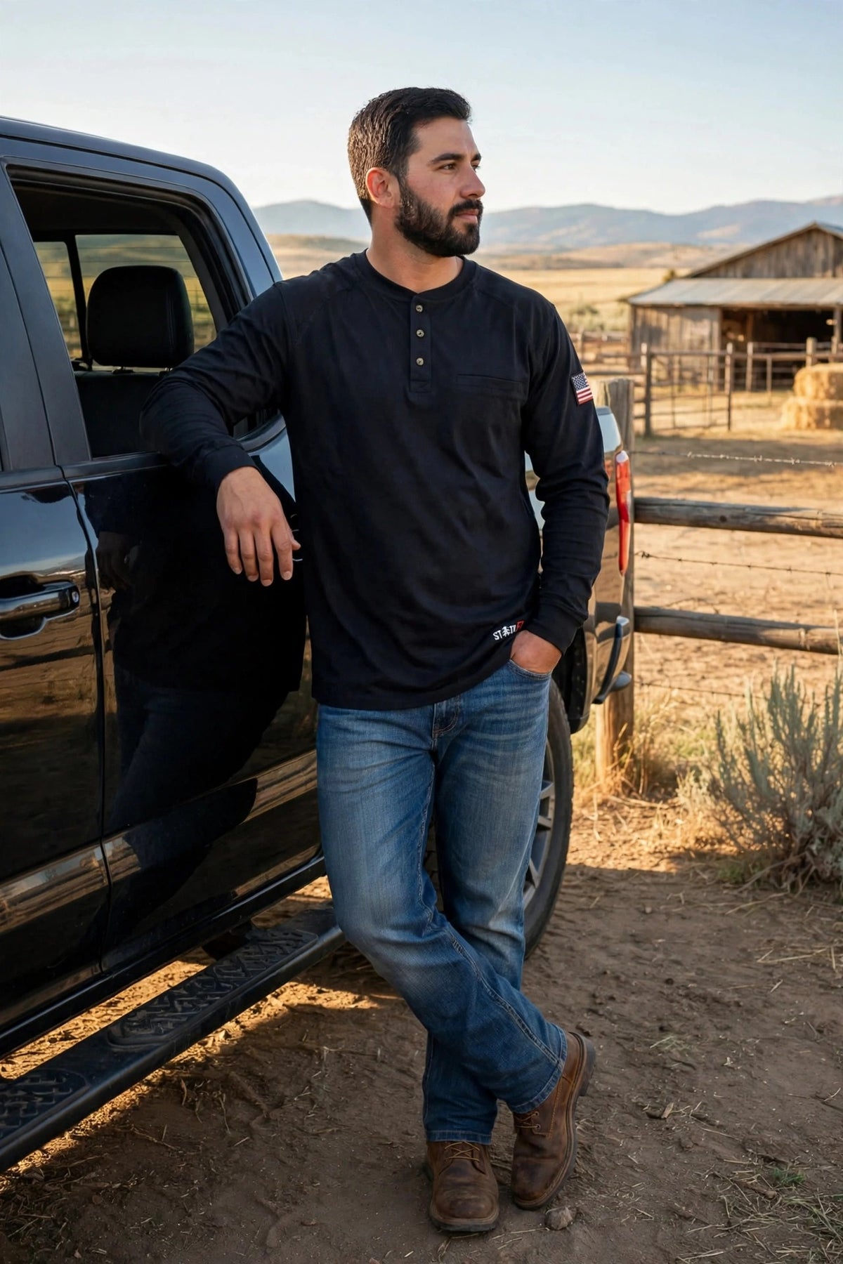 Black FR Henley worn with jeans and work boots by a pickup truck at a ranch
